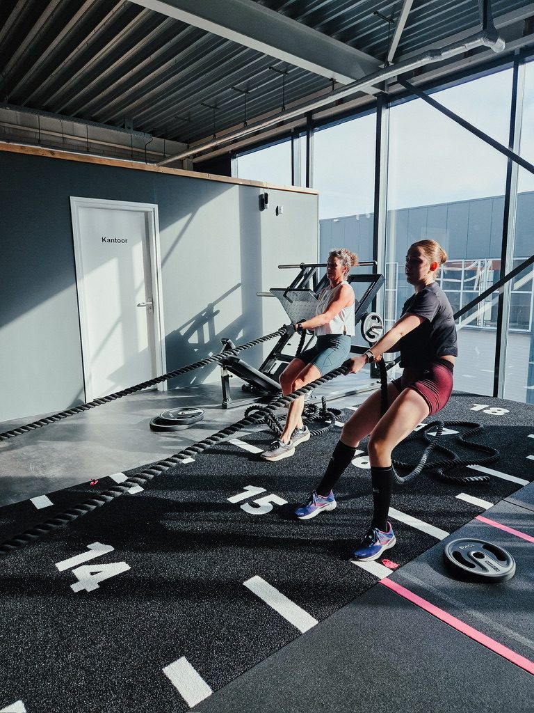 Twee vrouwen trainen samen met battle ropes