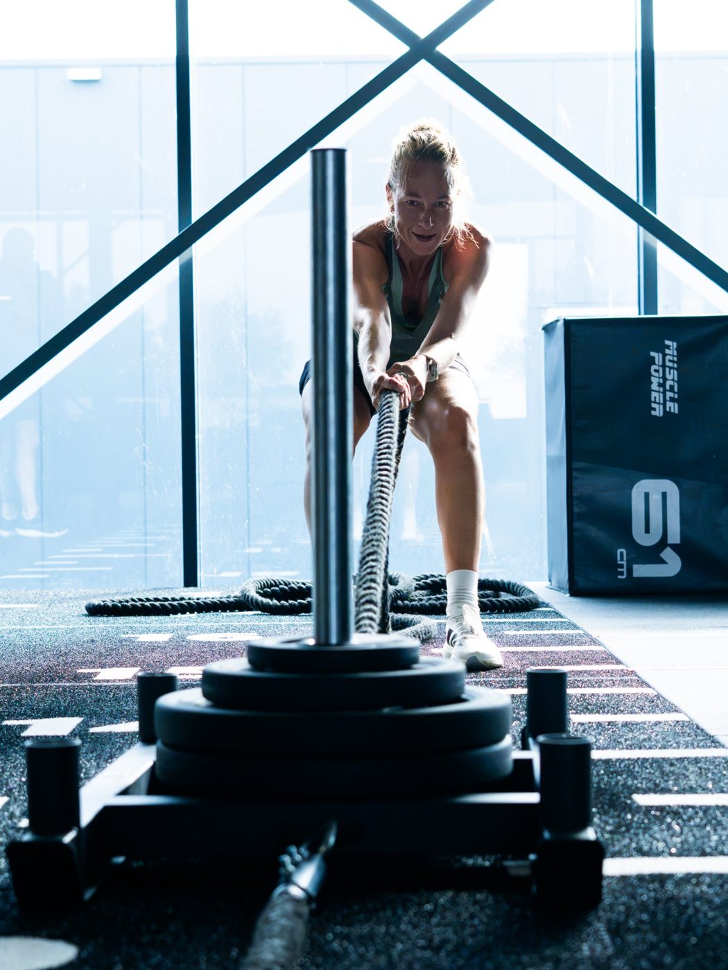 Sporter traint lachend met de battle rope in de studio van Exclusive Gym