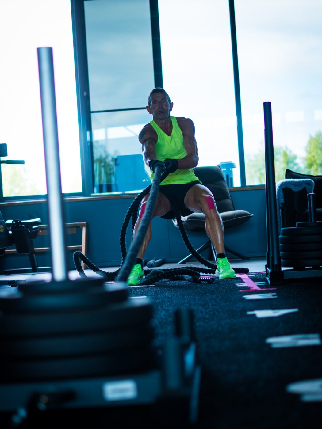 Sporter traint met battle ropes bij de grote ramen