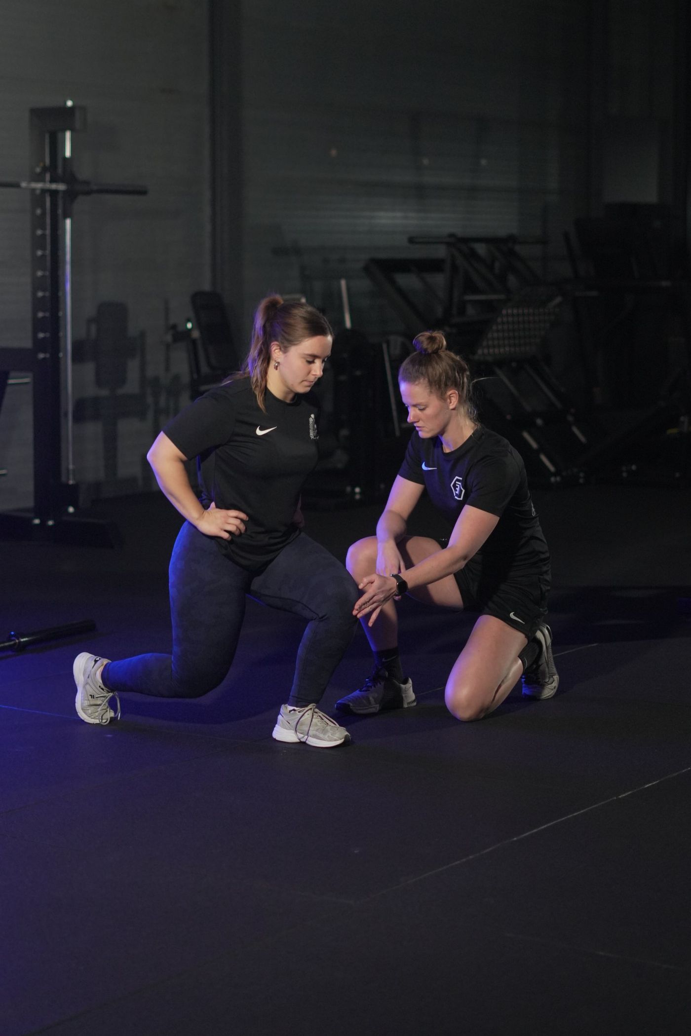 Coach corrigeert de techniek van een klant tijdens een lunge in de privé studio