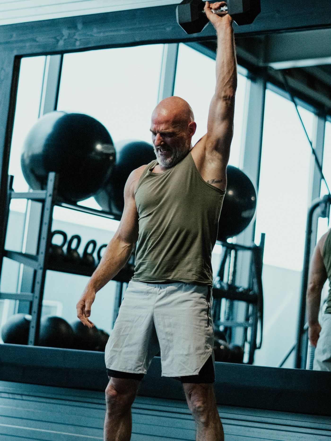Klant doet een overhead press met een dumbbell