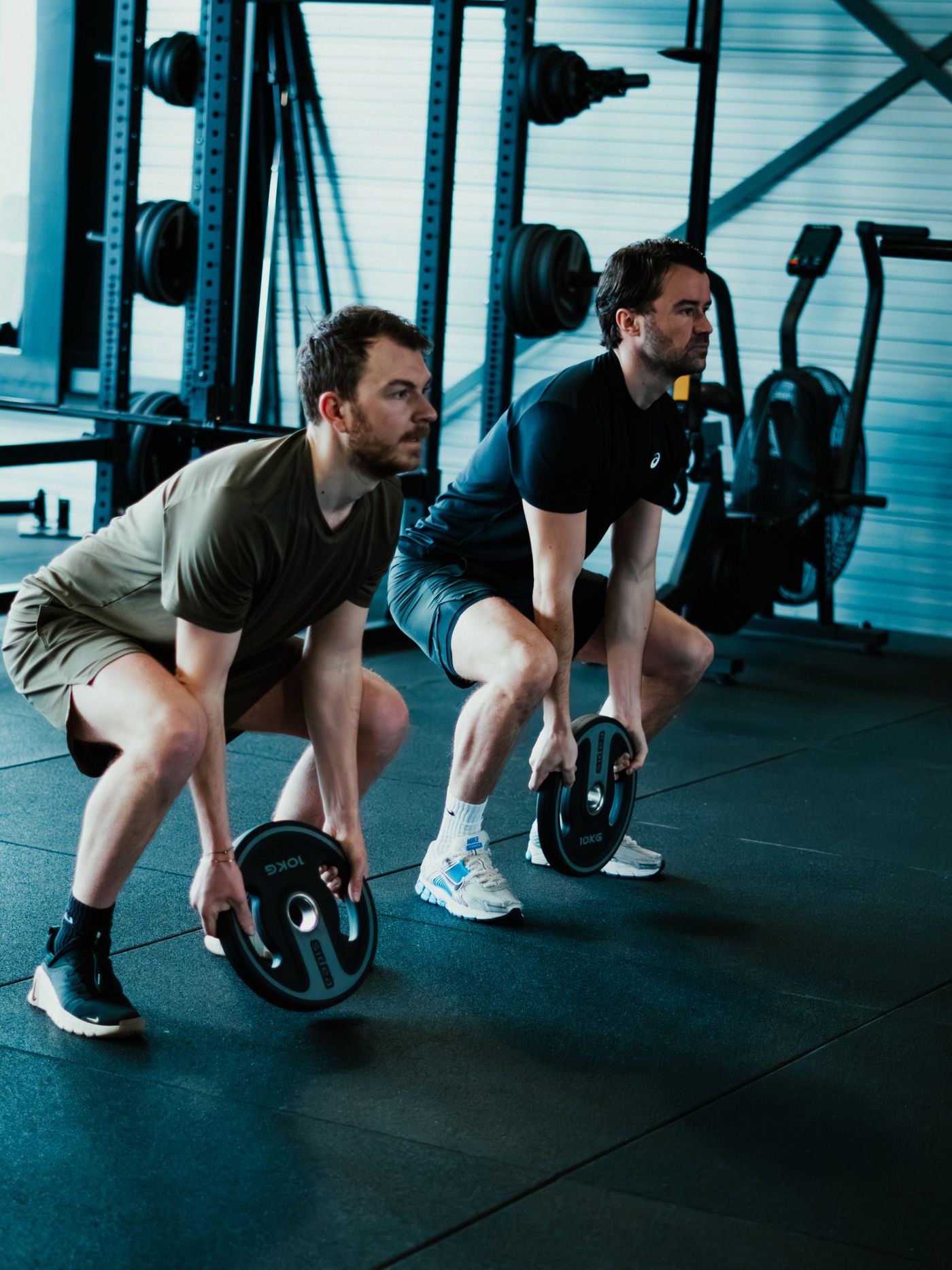 Twee sporters doen samen een deadlift met halterschijven