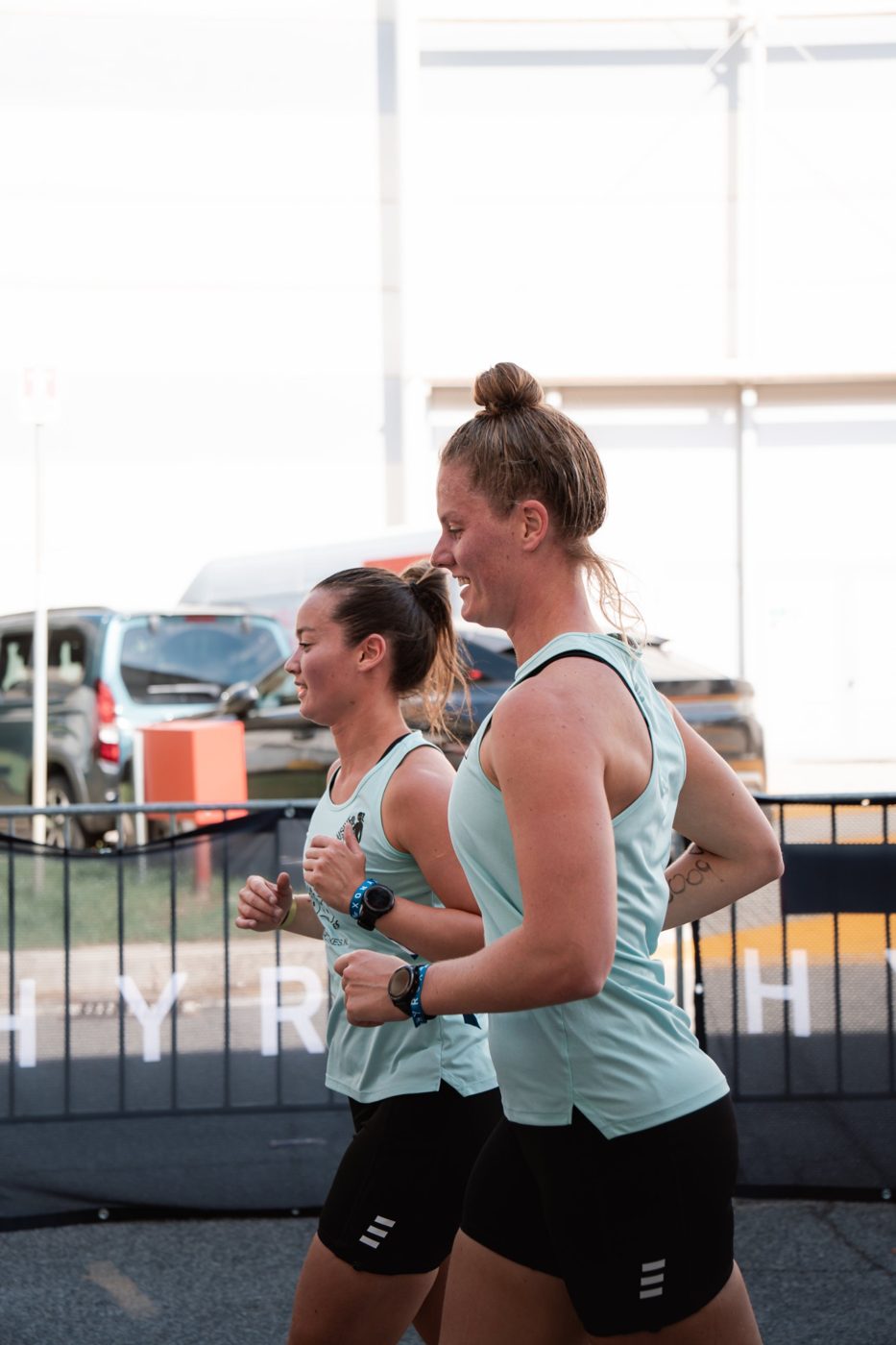 Twee sporters van Exclusive Gym rennen lachend tijdens een HYROX-evenement