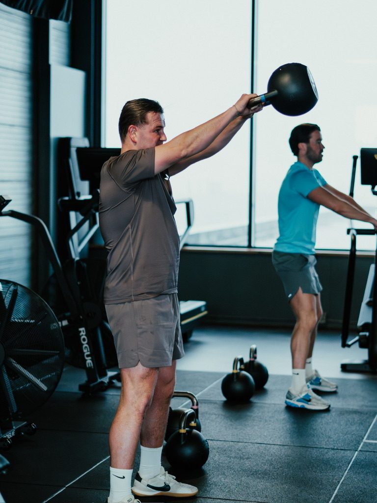 Twee mannen doen kettlebell swings naast elkaar