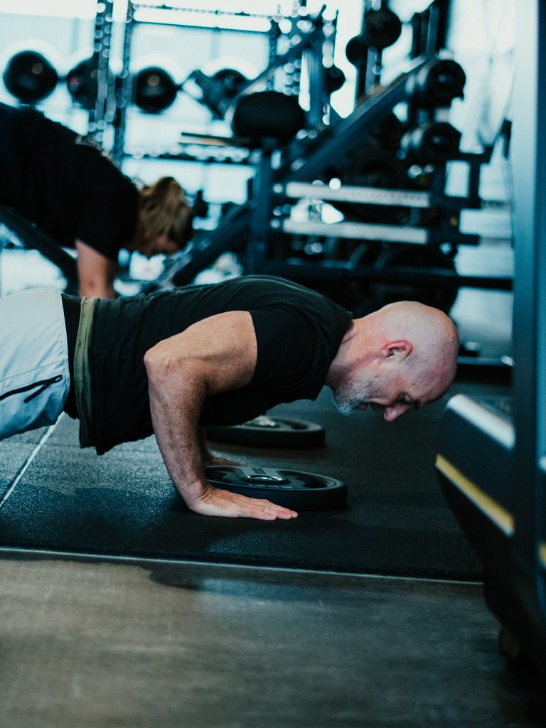 Push-ups met een halterschijf tijdens een groepstraining
