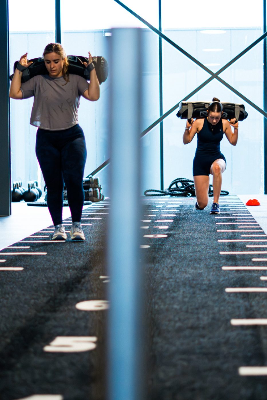 Twee vrouwen doen sandbag lunges op de sledbaan