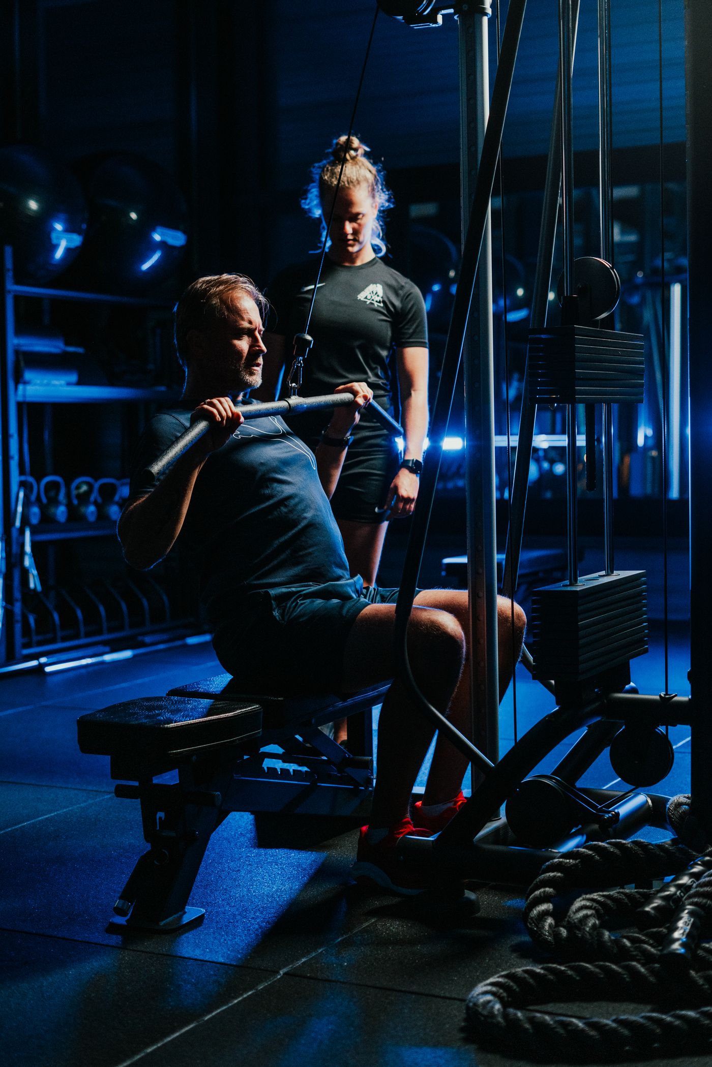 Coach begeleidt een klant aan de kabelmachine in de privé studio van Exclusive Gym in Den Helder